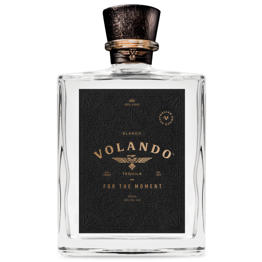 Bottle of Paramount Volando Tequila Blanco 750mL with clear glass and white label on a wooden surface.